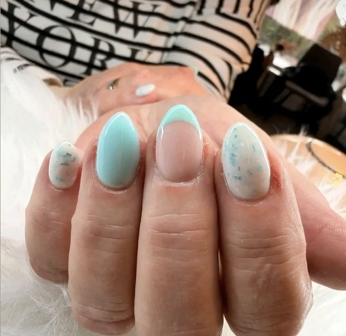 Hand met lichtblauwe BIAB-nagels, deels gespikkeld, op wit bont